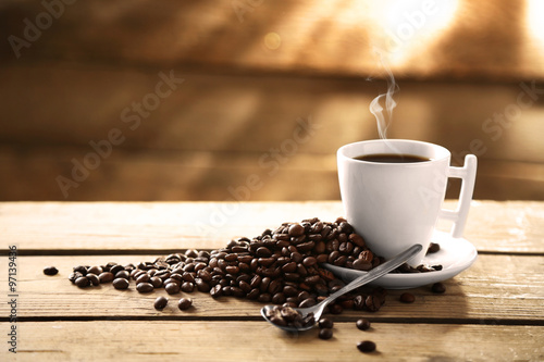Cup of coffee and coffee grains on wooden background