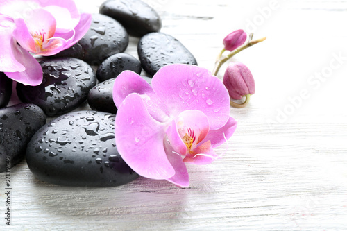 Beautiful composition of orchid and pebbles on white wooden background  close up