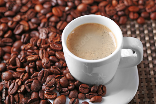 Cup of coffee and coffee grains on dark background