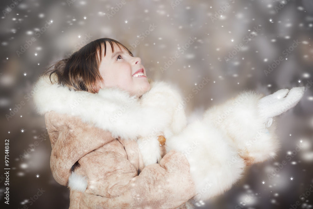 A cute little girl in a fur coat enjoys the falling snow A cute little girl in a fur coat enjoys the falling snow