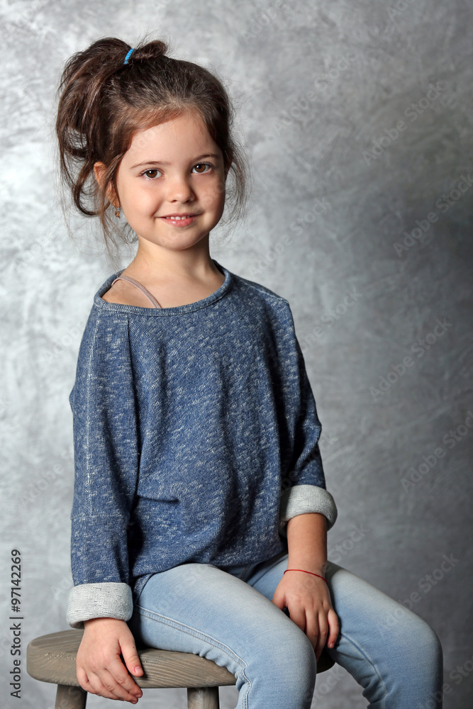 Portrait of little fashion kid girl on gray wall background