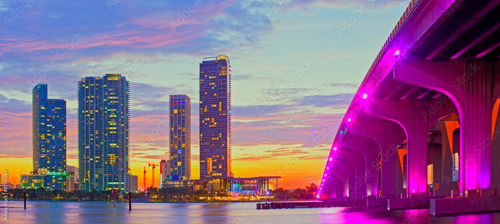 Obraz premium Miami na Florydzie o zachodzie słońca, kolorowa panorama oświetlonych budynków i most na grobli Macarthur