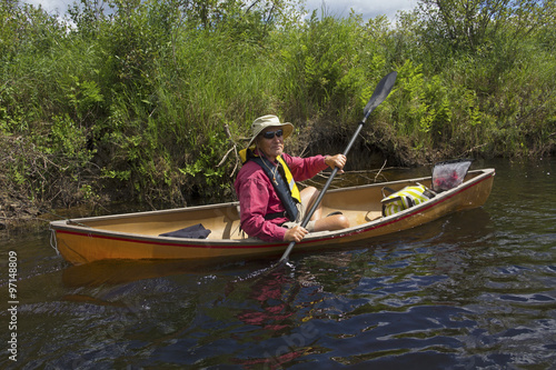 Senior man paddling a small canoe on the Moose River in the Adirondacks, New York.