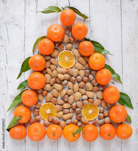 christmas tree of mandarins and nuts on old grunge wooden board
