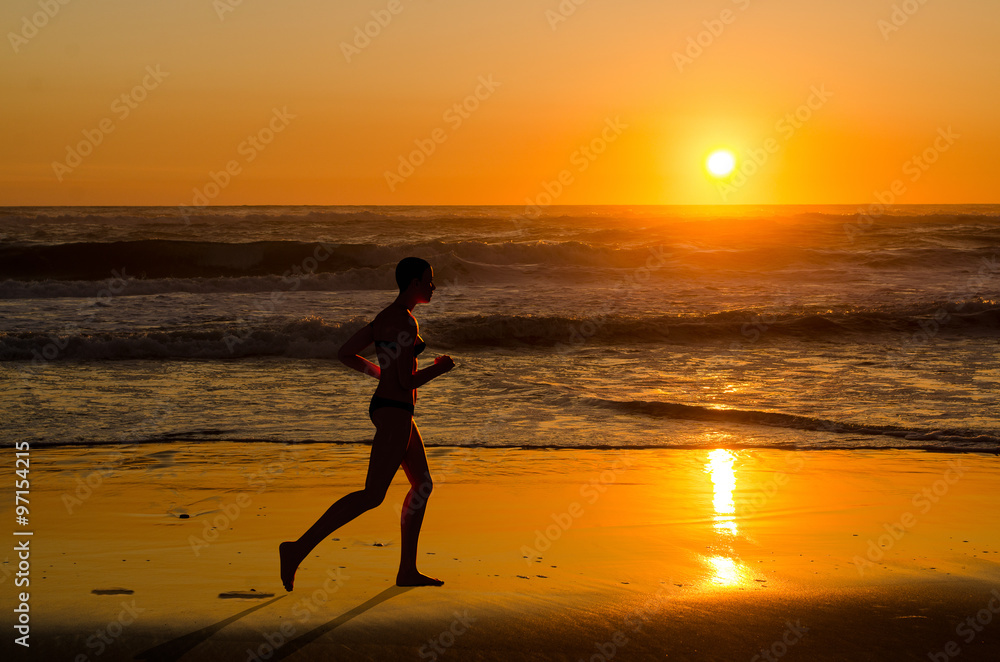 Woman jogger running on sunset beach