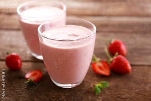 Fresh strawberry yogurt with berries around on wooden background