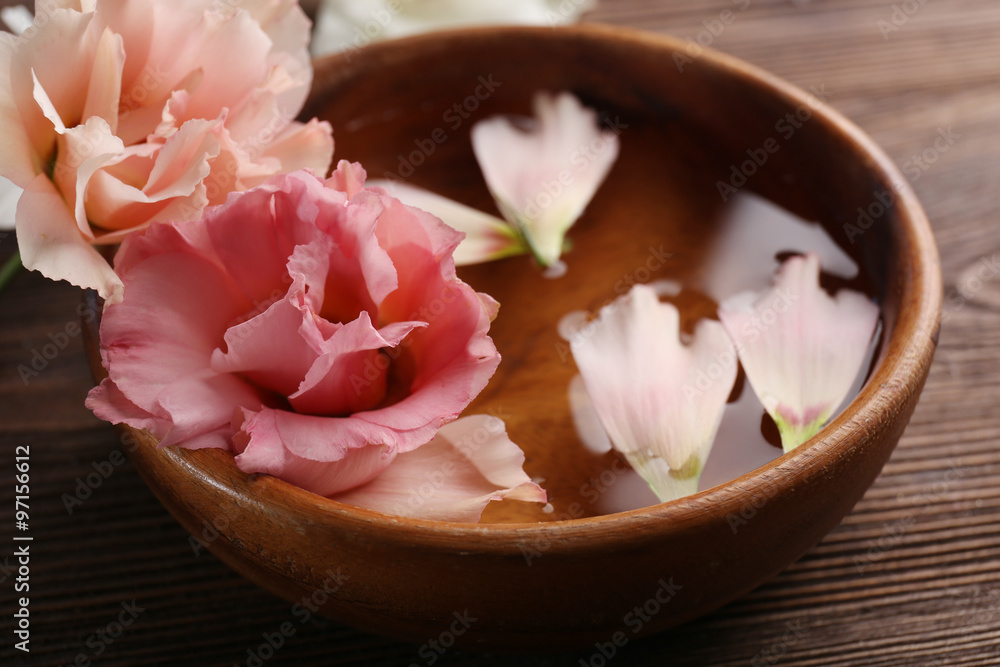 Pink rose and petals in a bowl of water on wooden background Pink rose and petals in a bowl of water on wooden background