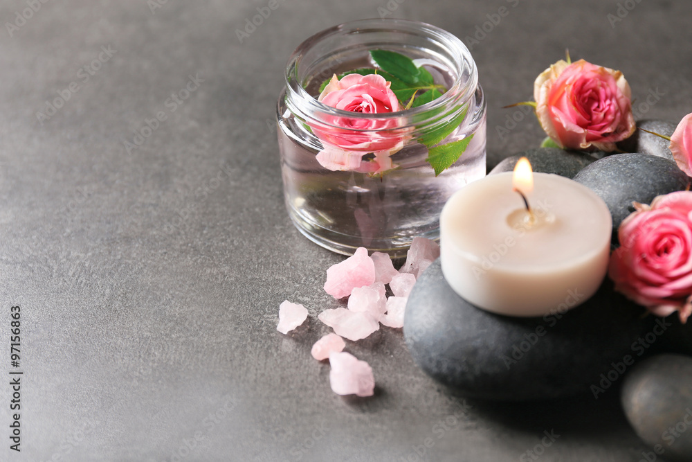 Spa composition of candles, stones and flowers, on grey background Spa composition of candles, stones and flowers, on grey background