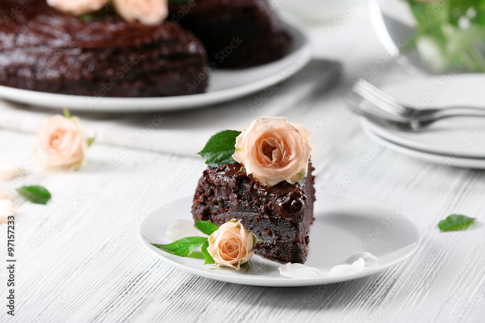 Piece of chocolate cake decorated with flowers on white wooden table Piece of chocolate cake decorated with flowers on white wooden table