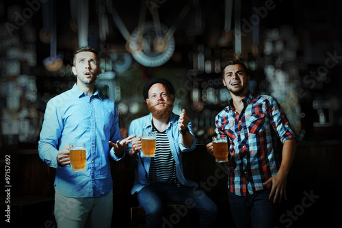 Young men with beer rejoice the victory of their favorite team in the pub © Africa Studio