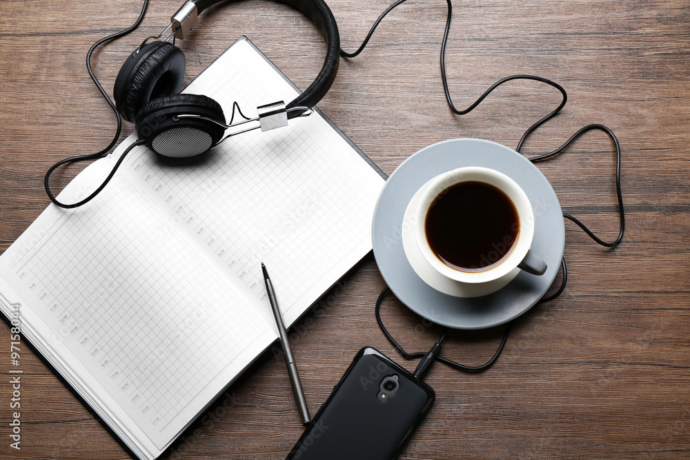 Headphones with papers and cup of coffee on wooden table Headphones with papers and cup of coffee on wooden table