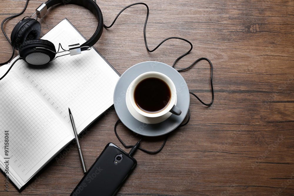 Headphones with papers and cup of coffee on wooden table - obrazy, fototapety, plakaty 