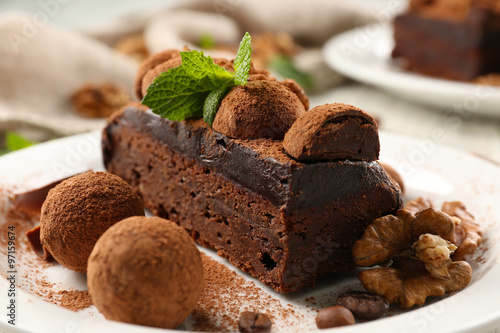 Chocolate balls, a piece of cake with walnut and mint on the table, close-up
