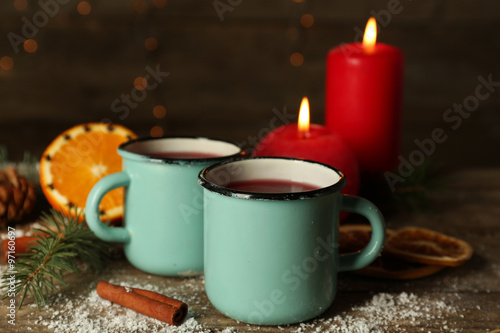 Decorated composition of mulled wine in mugs on wooden table