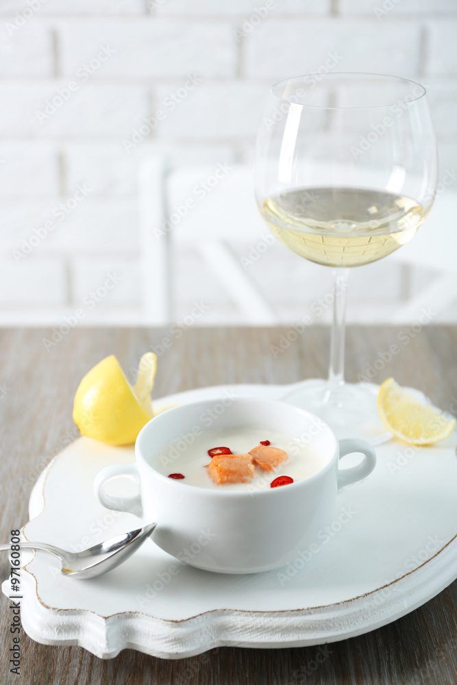 Tasty salmon cream soup, wine and lemon on wooden table, close up Tasty salmon cream soup, wine and lemon on wooden table, close up