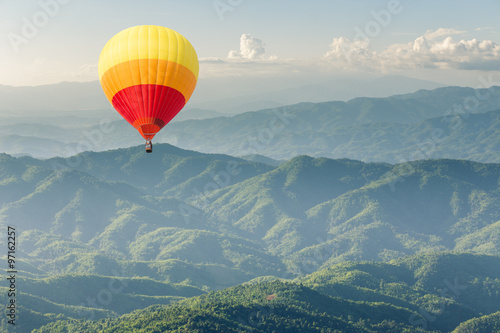 Colorful hot air balloon above forest mountain © littlestocker