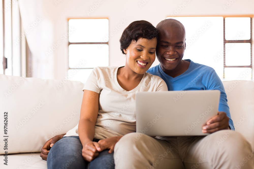 african couple looking at laptop screen african couple looking at laptop screen