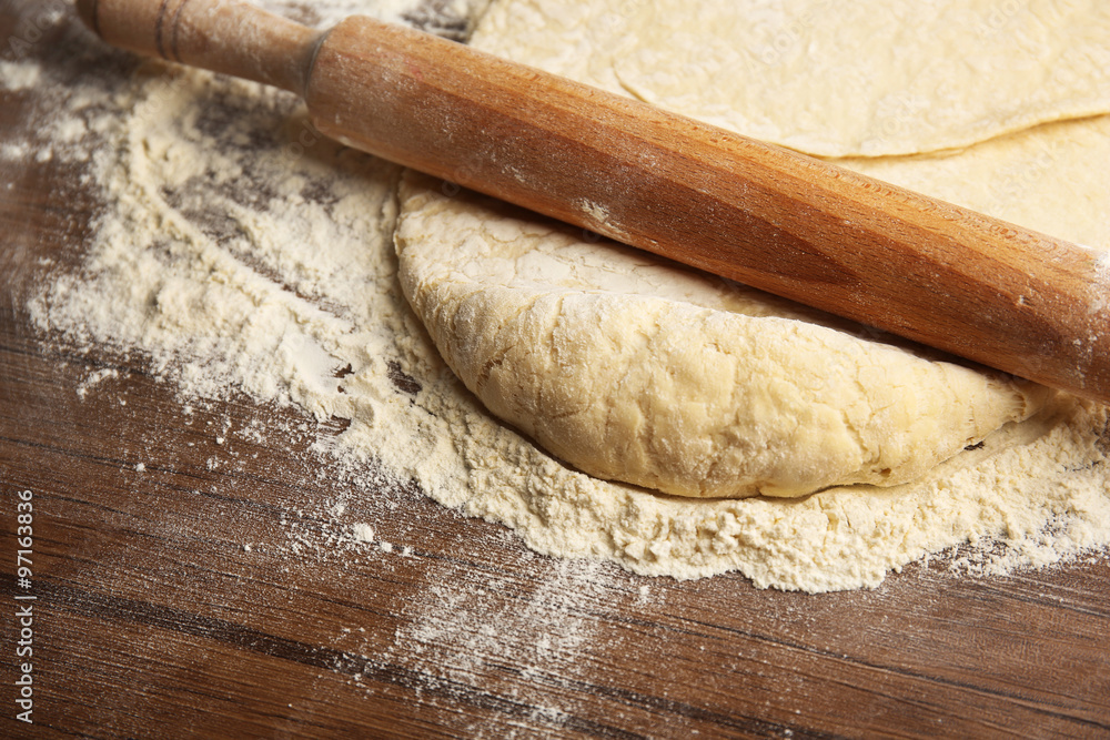 Dough for pizza and rolling-pin on wooden table Dough for pizza and rolling-pin on wooden table