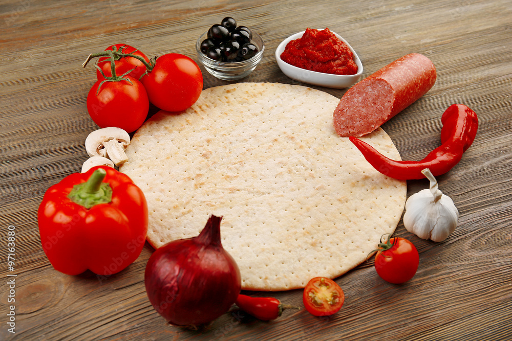 Dough basis and ingredients for pizza in the shape of circle, on the table Dough basis and ingredients for pizza in the shape of circle, on the table