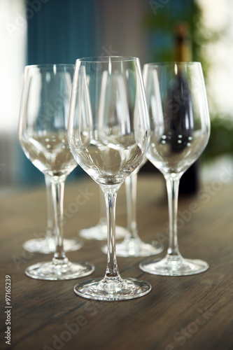 Empty wine glasses with bottle on wooden table against blurred background