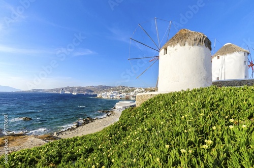 Three windmills in Chora,Mykonos,Greece.Traditional greek whitewashed architecture,popular landmark,tourist destination against blue sky and Aegean sea over Little Venice.Wind mills are now decorative photo