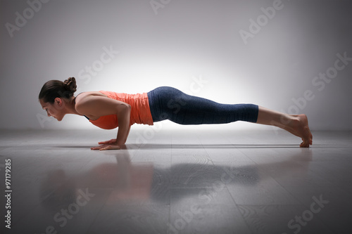 Woman practices yoga asana Chaturanga Dandasana photo