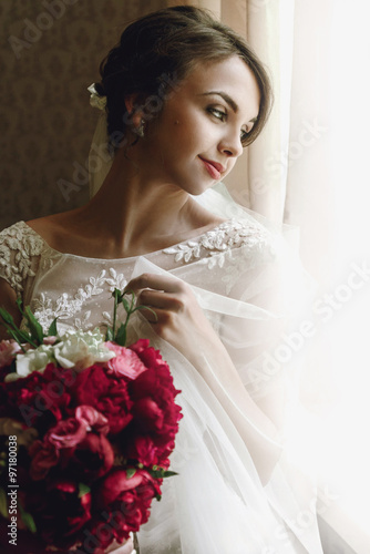 gorgeous happy luxury stylish brunette bride with bouquet near a
