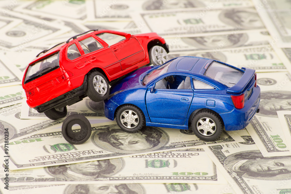 Toy cars in accident on a background of 100 dollar bills

