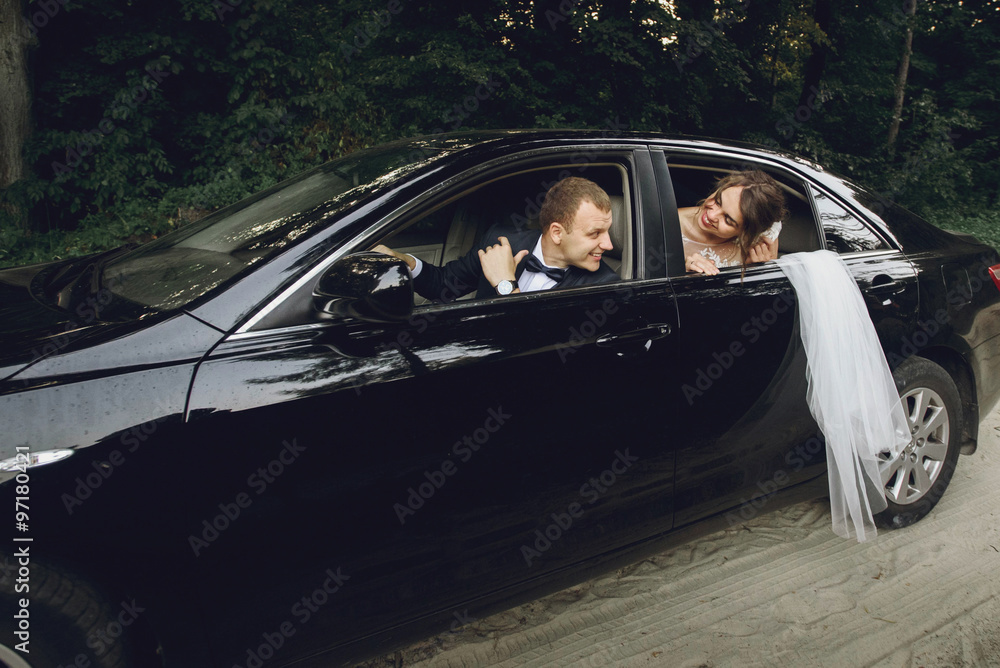 gorgeous elegant happy bride and stylish groom driving in luxury