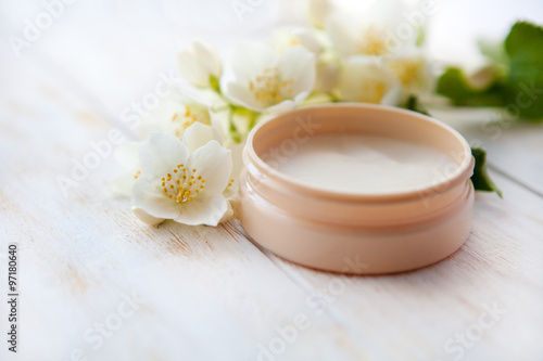   Spa setting with pot of beauty cream and sea salt on white wooden table