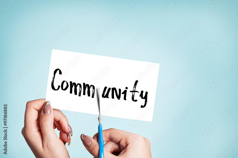 Woman hands cutting card with the word community Woman hands cutting card with the word community