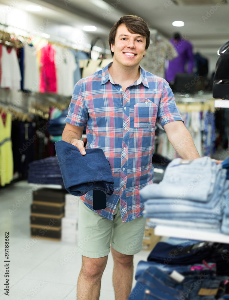 male chooses jeans at clothing store