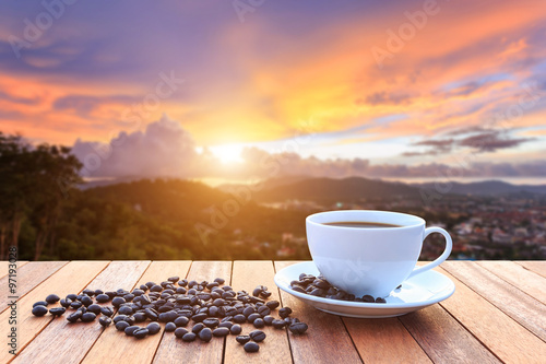 White coffee cup and coffee beans on wood table and view of suns