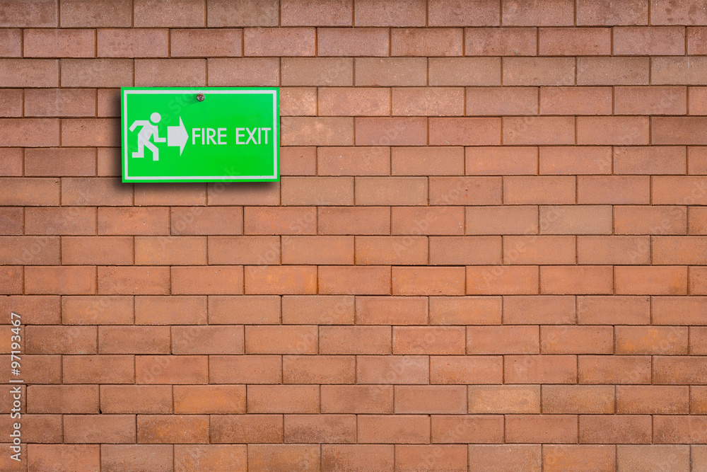 Green fire exit sign on stone wall Green fire exit sign on stone wall