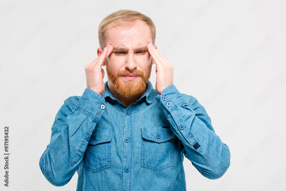 Young depressed bearded man touching his temples and having headache Young depressed bearded man touching his temples and having headache