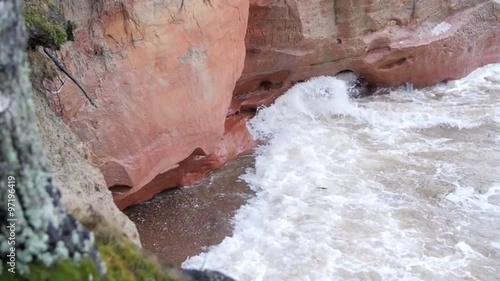 Waves hitting sandstone cliffs during a winter storm in slow motion photo