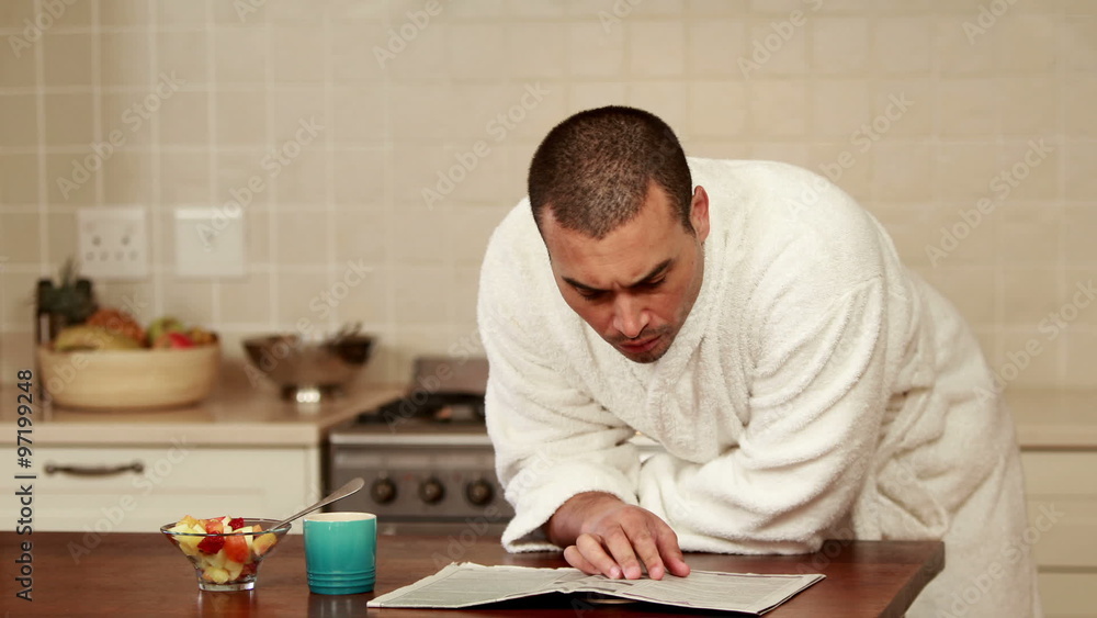 Smiling man wearing bathrobe reading newspaper Smiling man wearing bathrobe reading newspaper