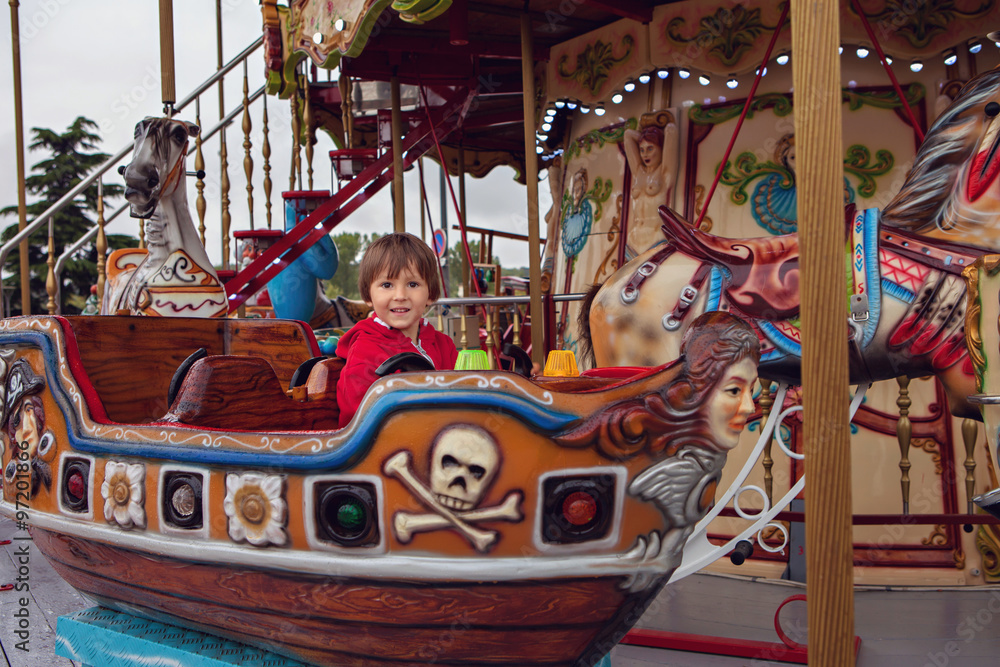Sweet boy, riding in a train on a merry-go-round, carousel attra