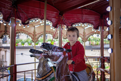 Sweet boy, riding in a train on a merry-go-round, carousel attra