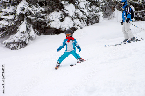 Adorable little boy with blue jacket and a helmet, skiing in win