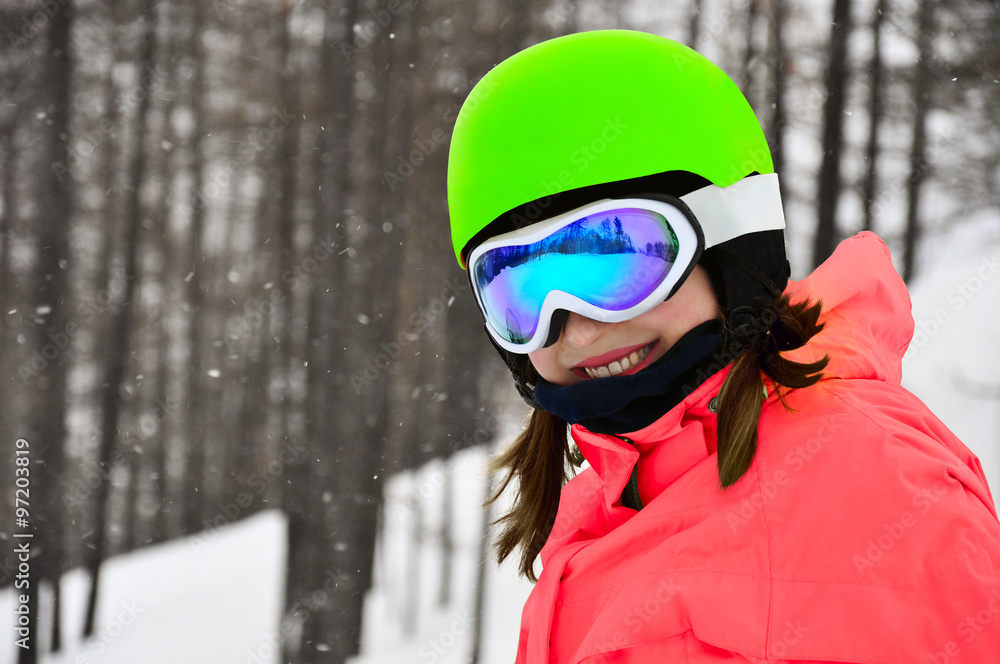 Smiling girl in snowboard glasses and helmet