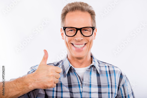 Handsome happy aged man in glasses gesturing thumb up