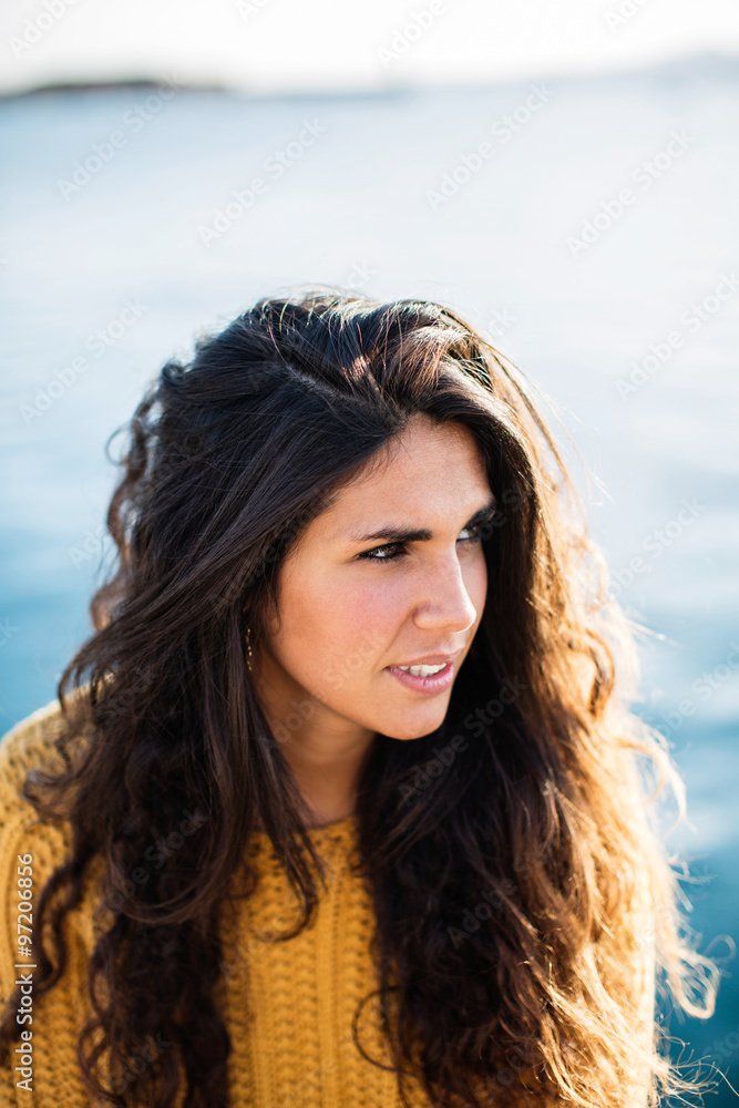 Portrait of young woman looking away while sitting on pier