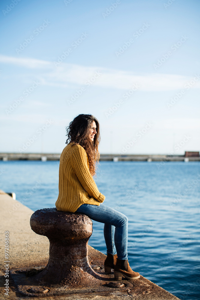 Side view of young woman sitting on pier