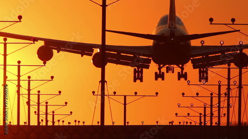 HD footage of a 4 engine jumbo jet plane landing in silhouette against an orange sunset sky.  Jet engine audio included.