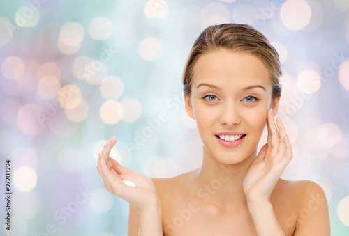 happy young woman applying cream to her face