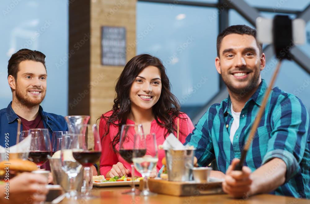 friends taking selfie by smartphone at restaurant friends taking selfie by smartphone at restaurant