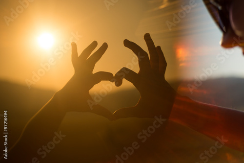 hands forming a heart shape with sunset silhouette. instagram fi