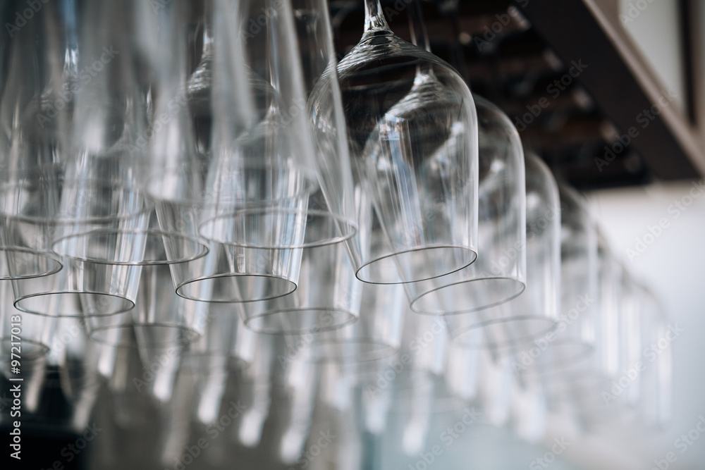 Empty glasses for wine above a bar rack. Hanging wine glasses in Empty glasses for wine above a bar rack. Hanging wine glasses in