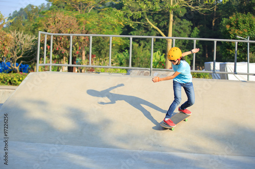 skateboarding young woman riding on a skateboard at skatepark